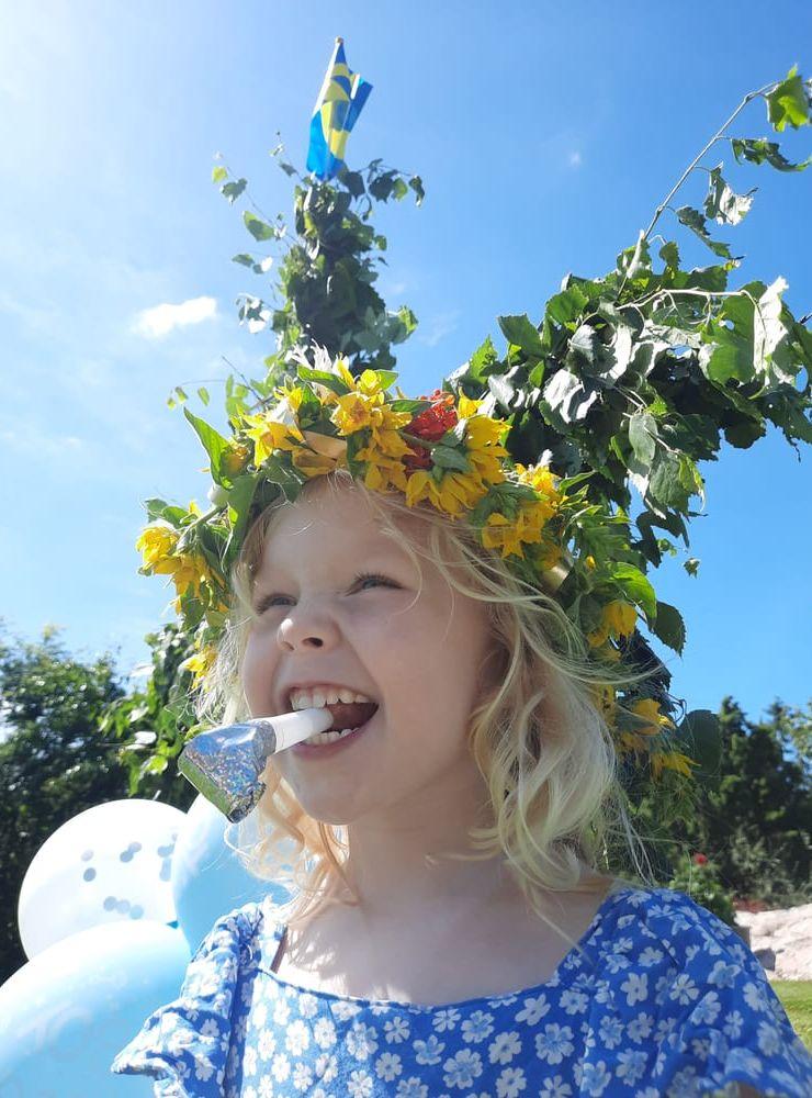 Framför en midsommarstång hemma hos mormor och morfar står Agnes 4 år redo att fira midsommar. 